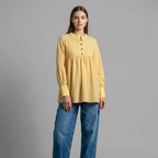 Woman wearing a yellow checkered blouse and blue jeans on a gray background